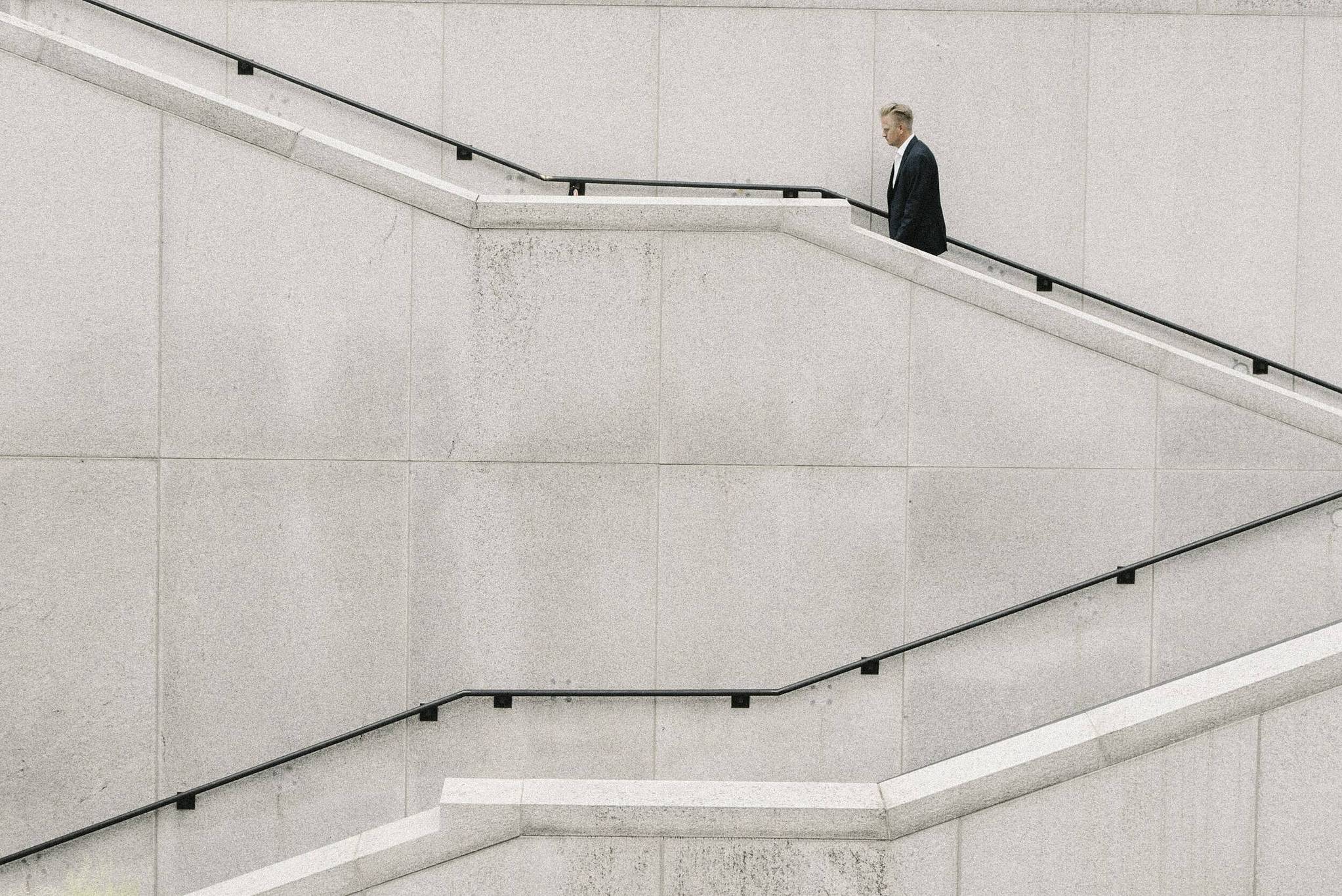 Mann im Anzug läuft graue Treppe eines Gebäudes hinauf